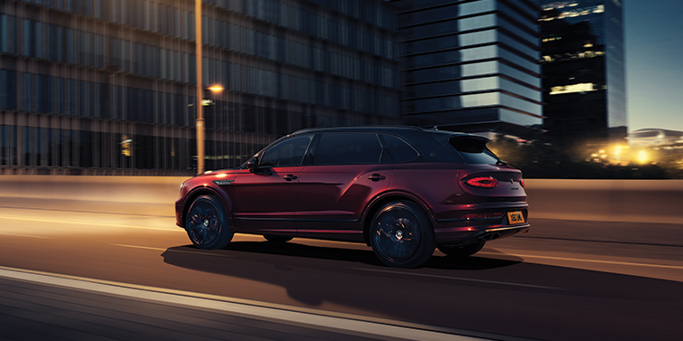 Bentley New Delhi Bentley Bentayga Extended Wheelbase Mulliner SUV in Cricket Ball red paint driving dynamically in city at night